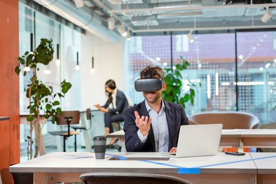 Employee with VR googles gesturing in office