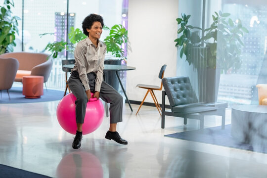 Manager bouncing on hopper ball in office