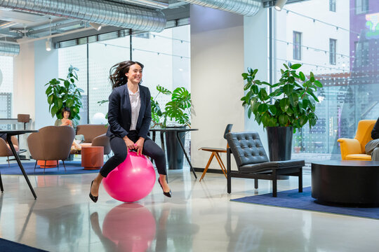 Playful young employee bouncing on hopper ball in office lobby