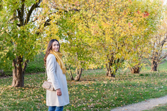 Smiling young woman spending leisure time in autumn park
