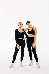 Portrait of two fit young women standing over white background