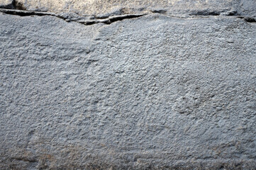 The concrete base of the house, the foundation is gray. A large monolith. Rough texture.