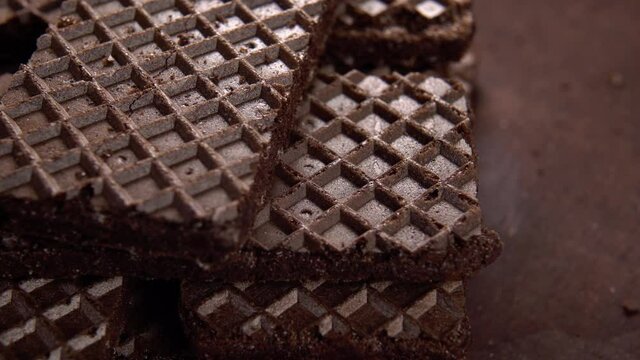 Stacked crispy chocolate wafer cookies on a wooden surface. Textured checkered pattern. Macro. Rotation