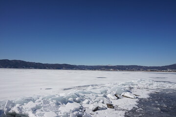 御神渡りが期待される凍った諏訪湖と湖岸に漂着した氷のブロック