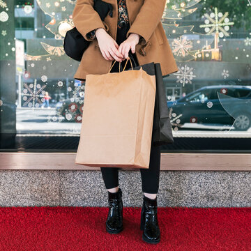 Woman holding shopping bags on footpath at Christmas