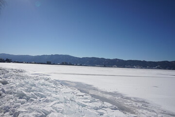 Fototapeta na wymiar 御神渡りが期待される凍った諏訪湖と湖岸に漂着した氷のブロック