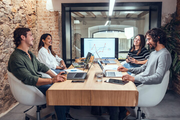 Smiling businessmen and businesswomen sitting at conference table in coworking office