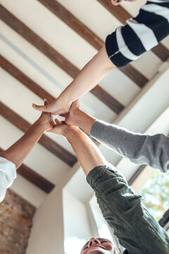 Multiracial colleagues high-fiving in coworking office