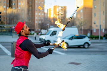 Street performer juggling flaming torches in city