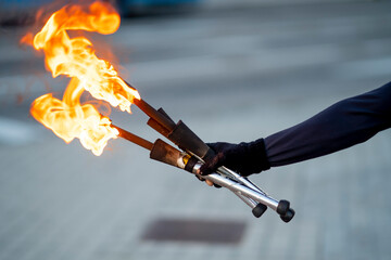 Hand of street artist holding flaming torches