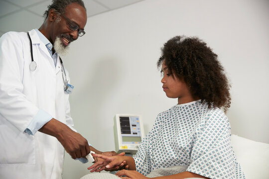 Doctor with pulse oximeter talking to patient at hospital