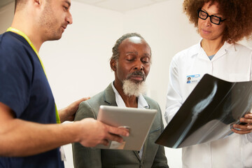 Nurse and doctor discussing with patient in medical room