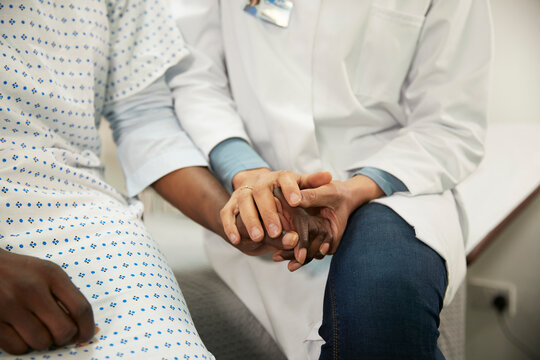 Doctor holding hands and consoling patient in medical room