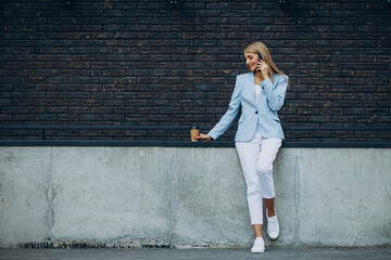 Young business woman drinking coffee and talking on the phone