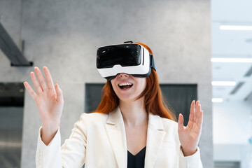 Excited working woman wearing virtual reality simulator gesturing with mouth open at office