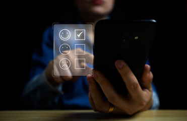 Customer Service Assessment Concept business woman using a smartphone and she is pressing the face emoticon Smile with satisfaction on the virtual touch screen.