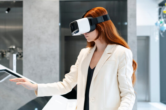 Businesswoman wearing virtual reality simulator and using touch screen device at workplace - Powered by Adobe