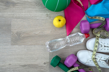Women's sports colored dumbbells and rubber bands for fitness top view.