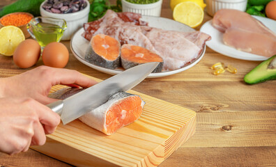 Female hands cutting salmon slices on wooden board. Cooking process, copy space.