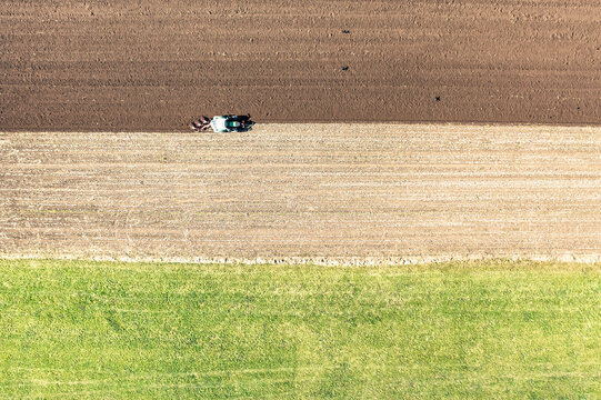 Drone view of tractor plowing field on sunny day