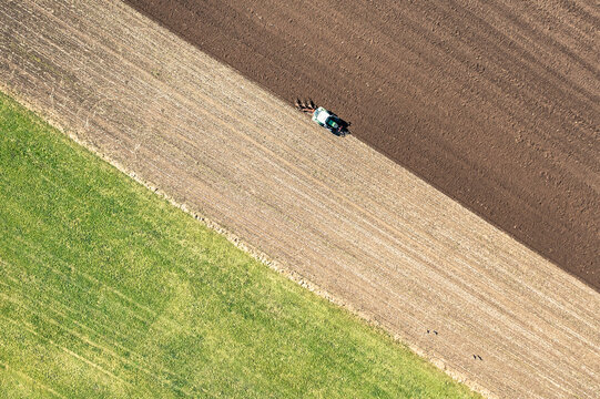 Aerial view of tractor plowing field on sunny day