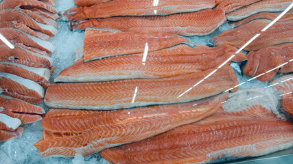 Fresh raw salmon fillet on ice on the counter in a fish store. red fish fillets in the glass...