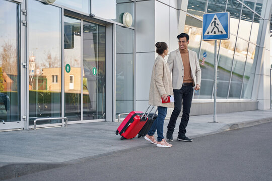 Cheerful male staring at his female partner near airport door