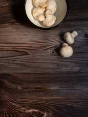 white rustic pewter bowl with raw mushrooms on dark wood
