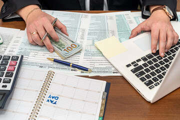 a business man in a jacket fills out tax forms and makes calculations at the table.