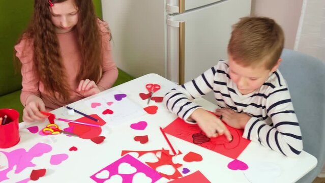 Kids, children, doing Valentine's Day arts and crafts with hearts, pencils, paper. Gift, surprize for mom. Children boy, lov Handmade decorations for holiday. Prepare for Valentine Day. Painting, DIY.