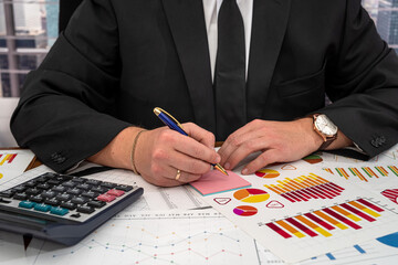 chic young male businessman calculates his business graphs at the office desk.