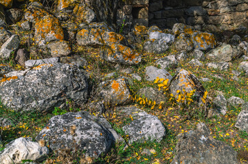 An abandoned medieval town. A complex of towers in the mountains of Ingushetia. View of the yellowed old stones of the destroyed wall of an ancient structure