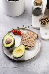 Ingredients for Healthy crunchy crisp bread sandwich: avocado, crackers and cherry tomatoes on round scandi plate