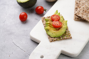 Healthy crunchy crisp bread sandwich with avocado and cherry tomatoes on marble board