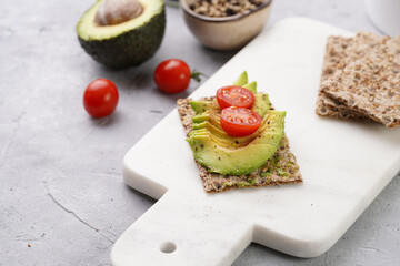 Healthy crunchy crisp bread sandwich with avocado and cherry tomatoes on marble board