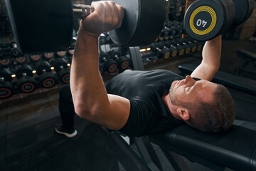 Serious male weightlifter doing upper-body weight-training exercise