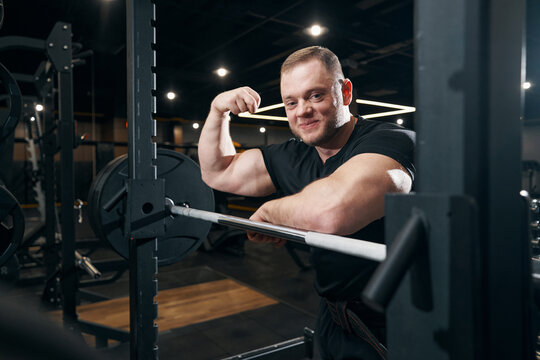 Smiling bodybuilder showing his strength during gym photo shoot