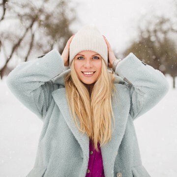 Attractive european blonde woman in winter expresses emotion of happiness against the background of snow