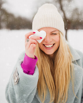 Attractive European blonde woman in winter with a heart made of ice - ice heart Valentine day - making snowballs to lovers