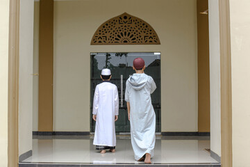 Back view two Islamic boarding school students are walking towards the mosque to pray