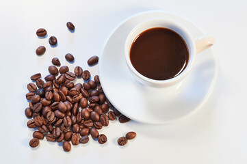 Cup of coffee and roasted coffee beans over white background