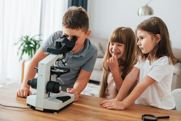 With microscope. Kids having fun in the domestic room at daytime together