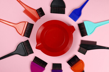 Hair coloring tools - plastic dye bowl and brushes on pink background