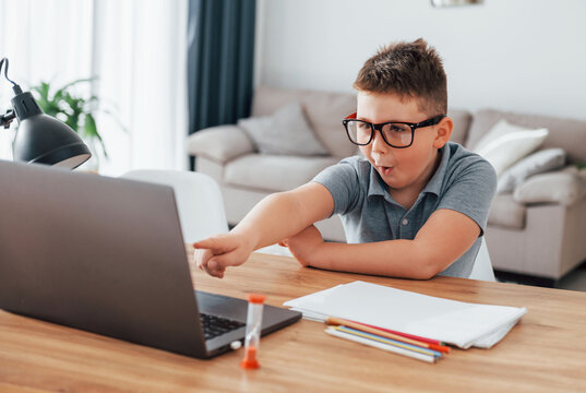 Little boy is having online lessons by using laptop at home