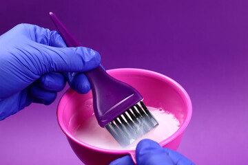 Hairdresser mixes hair dye in a plastic bowl