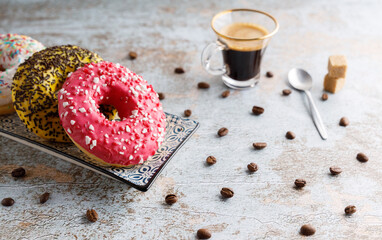 Variation of donuts. Assortment of colorful, delicious breakfast donuts, on a table top with a coffee on the side.