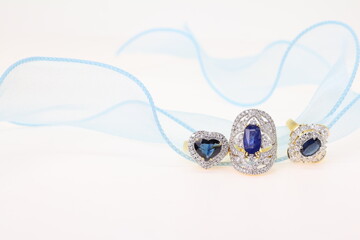 Blue Sapphire rings with Blue ribbon on white background. Jewelry set of gemstone and diamonds for...