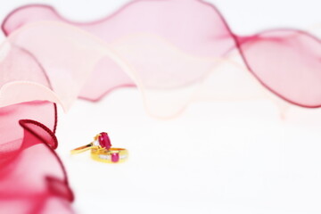 Obraz na płótnie Canvas Red ruby rings with pink ribbon on white background. Jewelry set of gemstone for shop