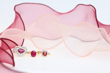 Red ruby rings with pink ribbon on white background. Jewelry set of gemstone for shop