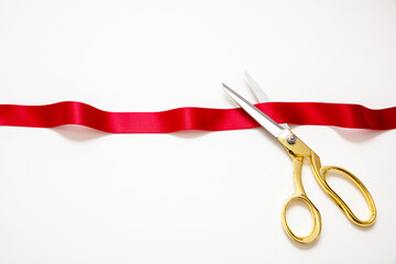 Grand opening, ribbon cut, overhead of gold scissors and red satin satin isolated on white